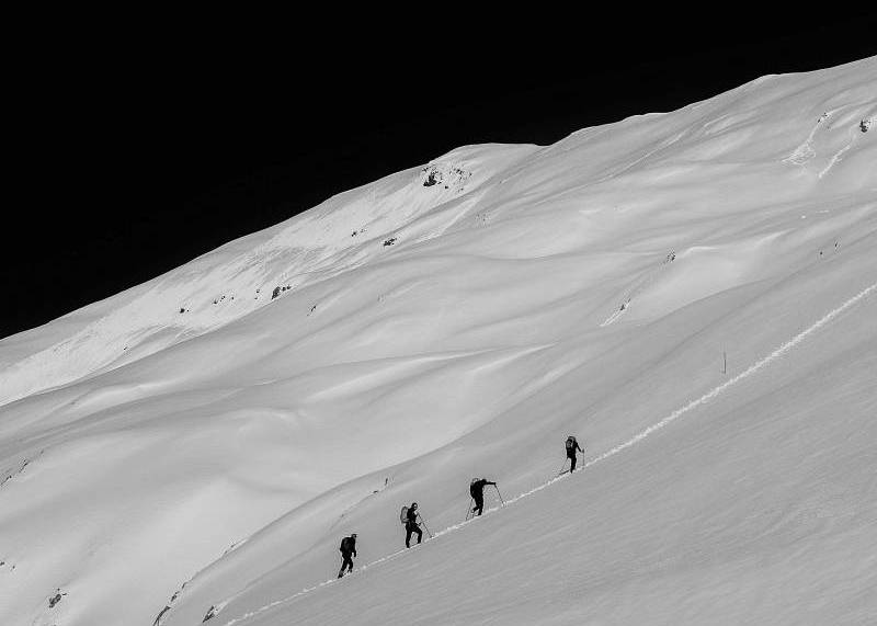 Team climbing a steep, snowy mountain